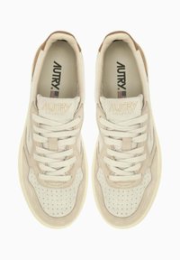 Sneaker beige in materiali scamosciati e in pelle, con punta forata, lacci crema, dettagli testurizzati e marchio "AUTRY" in rilievo.