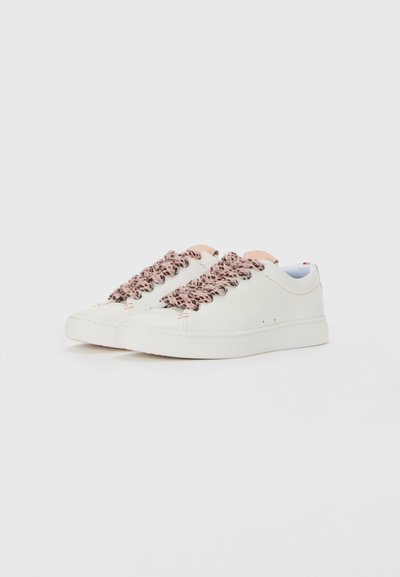 Sneakers bianchi a taglio basso con spesse stringhe rosa e nere a fantasia, accenti di linguetta rosa pallido, su uno sfondo bianco puro.