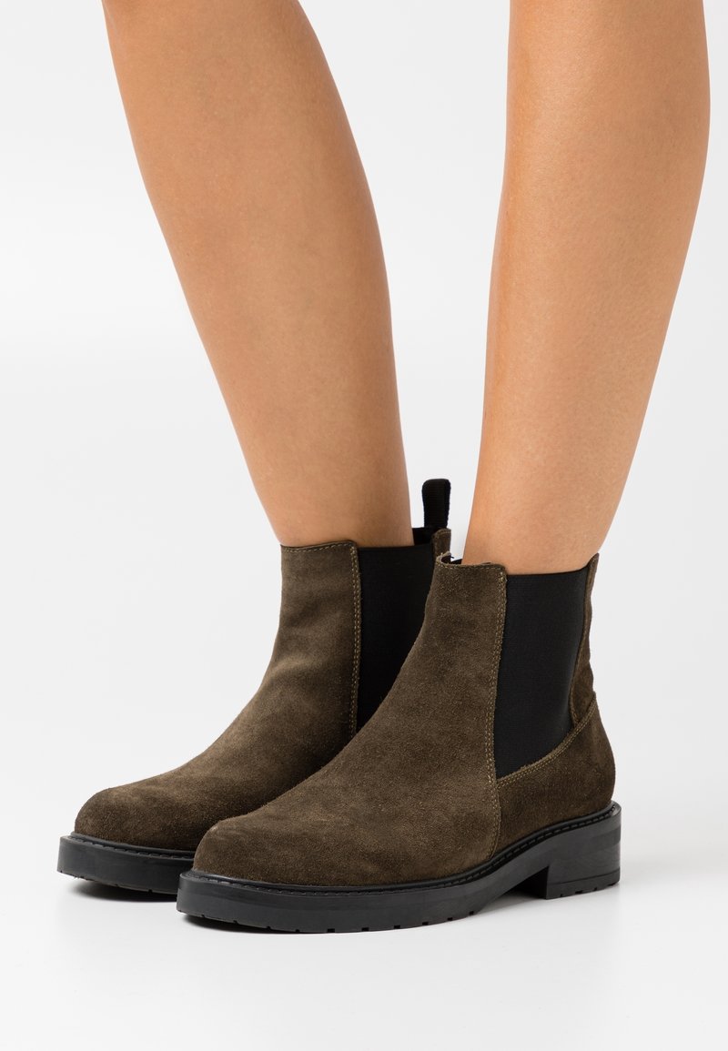 Ruske nubuk ankle bootsit, joissa on elastiset sivupaneelit ja teksturoitu musta pohja. Varressa on vetoketju, joka helpottaa pukemista.