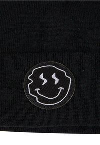 Schwarze gestrickte Mütze mit einem runden Patch, der ein lächelndes Gesicht und gewellte Linien zeigt, betont durch kontrastierendes weißes Nähen und eine weiche Textur.