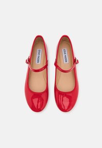Ballerines rouges en cuir verni avec un bout arrondi, dotées d'une sangle réglable et d'une doublure intérieure lisse.