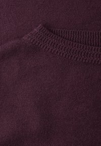 Bordeauxrode trui met een getextureerde geribde halslijn; zachte, gebreide stof met een gladde afwerking en subtiele kleurvariaties.