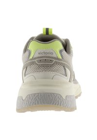Zapatilla deportiva gris con parte superior de malla, acentos en amarillo brillante, suela texturizada y una tira en la parte trasera, con el logo en el talón.