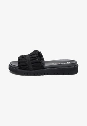 Black slide sandal with thick ridged sole and ruffled fabric strap across the top.