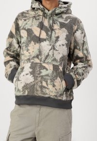Felpa con cappuccio in pile caratterizzata da un motivo mimetico nei colori verde, beige e grigio. Include una tasca frontale e cordini sul cappuccio.