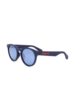 Occhiali da sole tondi blu navy con lenti azzurro chiaro e logo Adidas arancione sulla stanghetta, mostrati leggermente inclinati su sfondo bianco.
