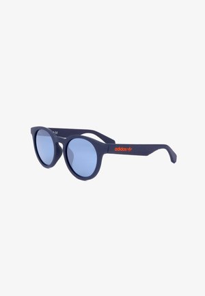 Occhiali da sole tondi blu navy con lenti azzurro chiaro e logo Adidas arancione sulla stanghetta, mostrati leggermente inclinati su sfondo bianco.