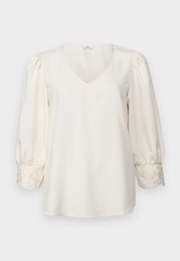 Blusa crema a scollo a V con maniche a sbuffo e accenti ricamati sui polsini. Tessuto morbido con vestibilità strutturata e bordi arrotondati.