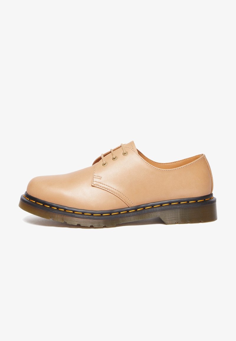 Chaussure derby en cuir beige avec trois œillets, couture jaune sur semelle en caoutchouc noire et semelle extérieure texturée pour une bonne adhérence.
