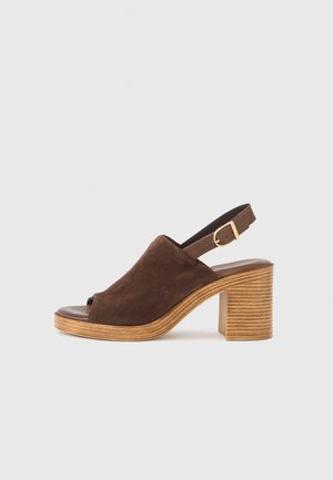 Brown suede open-toe slingback shoe with a stacked wooden heel and adjustable strap. Smooth inner lining and textured outer design.