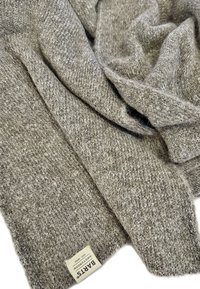 Brown knit scarf with a textured pattern, featuring a tag that reads "PARIS," with a soft, cozy appearance.