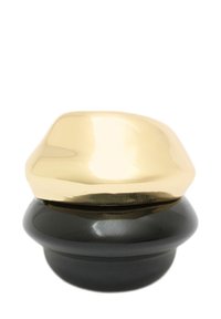 Keramický držák na prsteny v zlaté a černé barvě s hladkým zaobleným designem; zlatý vršek má lesklý povrch, zatímco černý základ je matný.