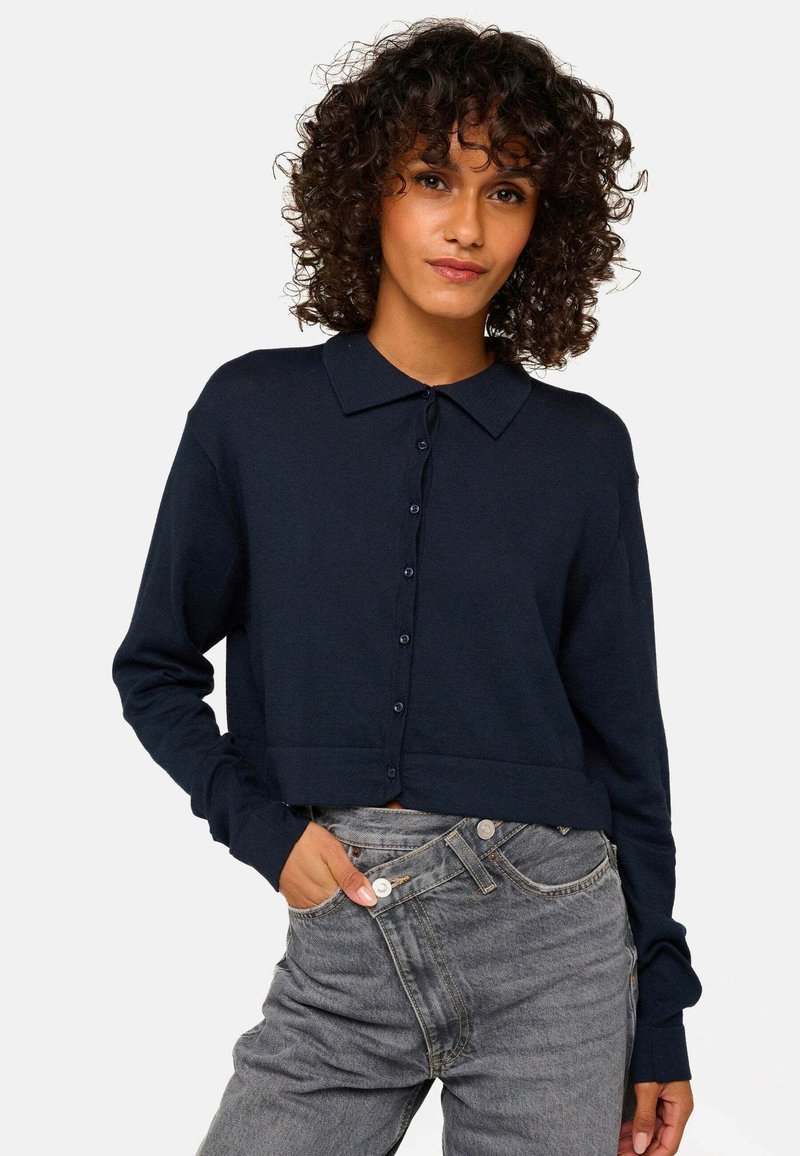 Cardigan bleu marine court à manches longues, avec fermeture à boutons et un col classique, fabriqué en matériau tricoté doux, présentant une texture lisse.