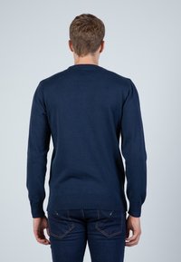 Marineblaue Strickjacke mit langen Ärmeln, rundem Ausschnitt, gerippten Bündchen und Saum; glatte Textur und lässige Passform. Rückansicht angezeigt.