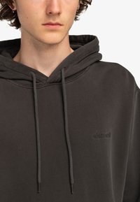 Charcoal gray hoodie with a drawstring, featuring a textured fabric and embossed logo on the chest. Soft, casual design with a relaxed fit.