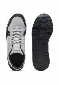 Scarpe sportive con tomaia in tessuto grigio, dettagli neri, lacci piatti e suola in gomma nera con motivo. Logo visibile sulla linguetta.