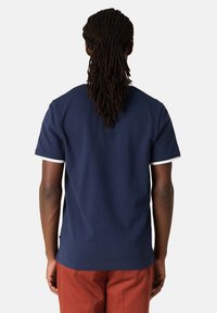 Granatowa bawełniana koszulka z okrągłym dekoltem, krótkimi rękawami z białymi wykończeniami oraz luźnym krojem. Gładka faktura, podstawowy design, bez grafik.