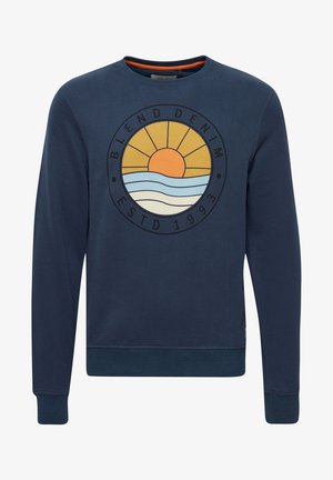 Tmavě modrá mikina z bavlny, se zaobleným výstřihem a pružnými manžetami. Na přední straně je grafika, která zobrazuje slunce a vlny s textem "BLEND DENIM."