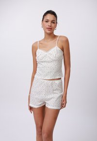 Conjunto de pijama con estampado floral en algodón suave; incluye una camiseta corta con adornos de encaje y pantalones cortos a juego con acentos de encaje y una cinturilla elástica.