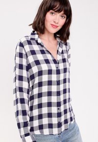 Chemise à manches longues en tartan bleu marine et blanc, avec un col boutonné, des boutons à l'avant et une coupe décontractée. Tissu texturé.