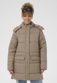 Beige polstret jakke med høj krave, trykknapdetaljer og to forlommer. Har et quiltet design og en glat tekstur.