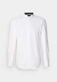 Camisa blanca de manga larga con cuello de banda, con botones en la parte delantera y un forro interno de patrón oscuro. Suave tela de algodón con un corte entallado.