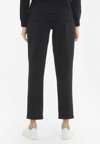 Black sweatpants with a straight-leg design, soft texture, and ribbed waistband. Paired with white sneakers.