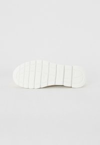 Biała gumowa podeszwa sneakersów z rowkowanym wzorem, pokazująca wzory przyczepności i odcisk logo dla lepszego chwytu. Charakteryzuje się gładką teksturą i zaokrąglonymi krawędziami.