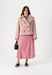 Kahe ridadega roosa tweedist jakk suurte pruunide nööpidega, kombineeritud pika roosa satiinskirti ja mustade kontsakingadega. Must kott on kaasas.