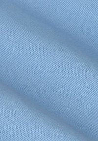 Gros plan sur un tissu bleu clair lisse avec une texture fine de tricot visible et des plis doux.