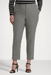 Black and white houndstooth patterned trousers with a slim fit, cropped length, side pockets, and a flat front, paired with black heeled sandals.