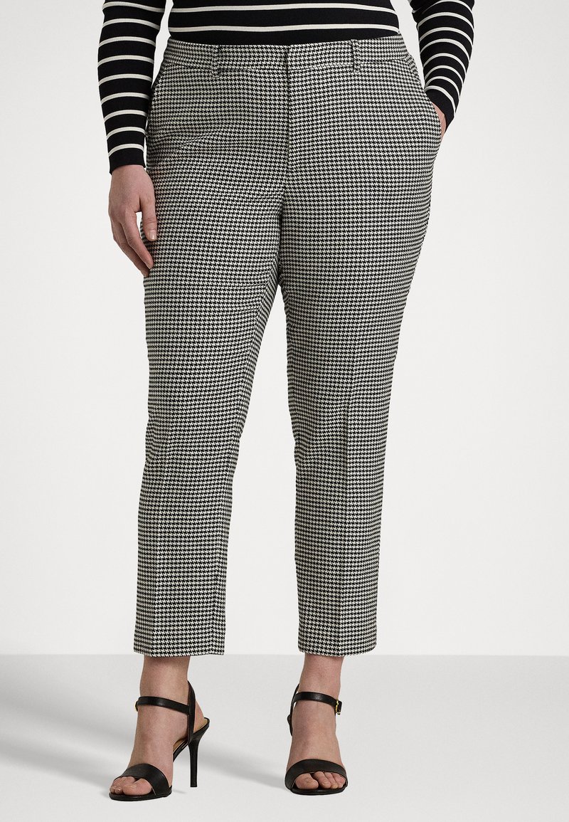 Black and white houndstooth patterned trousers with a slim fit, cropped length, side pockets, and a flat front, paired with black heeled sandals.