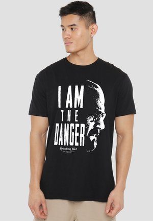 Black cotton t-shirt featuring a large white graphic of a face and the text "I AM THE DANGER" from Breaking Bad. Short sleeves, classic fit.