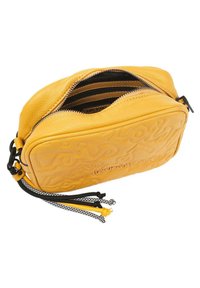 Bolso de cuero amarillo con diseño grabado, que cuenta con un cierre de cremallera, interior negro y acentos de cordón coloridos en amarillo, negro y blanco.