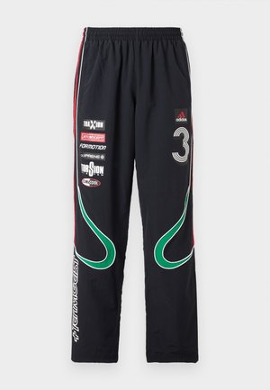 Czarne spodnie dresowe Adidas z zielonymi zakrzywionymi paskami, czerwonymi paskami bocznymi, numerem 3 i wieloma białymi logo sponsorów z przodu.