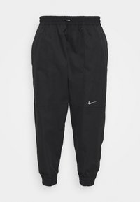 Svarta joggingsbyxor med elastisk midja, åtdragna muddar och sidofickor. Har en silverfärgad Nike-logotyp på vänster lår.