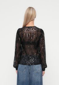 Kerge must blouse pikade varrukatega ja eheline tekstuur, ümar kaelus ja kehakujuline vöökoht, kombineeritud laia denimpliidiga.