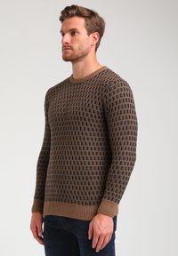 Brauner gestrickter Pullover mit geometrischem Muster, rippelndem Rundhalsausschnitt und Bündchen. Die Textur ist weich und die Passform slim.