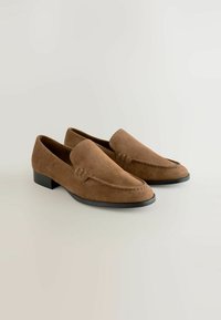 Mocassins en daim brun avec un talon noir plat, présentant une tige lisse, des détails cousus et un design à bout rond.
