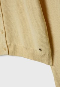 Cardigan en maille beige clair avec fermeture à boutons et un petit emblème métallique près de l'ourlet côtelé sur le devant.