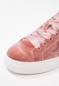 Rosa sammets sneakers med satinsnören, med en texturerad yta och vit gummisula. Inkluderar en stjärndesign på sidopanelen.