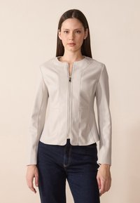 Lys grå imitert skinnjakke med rund hals, frontglidelås og tettsittende design, med vertikal søm og subtile formingsdetaljer.