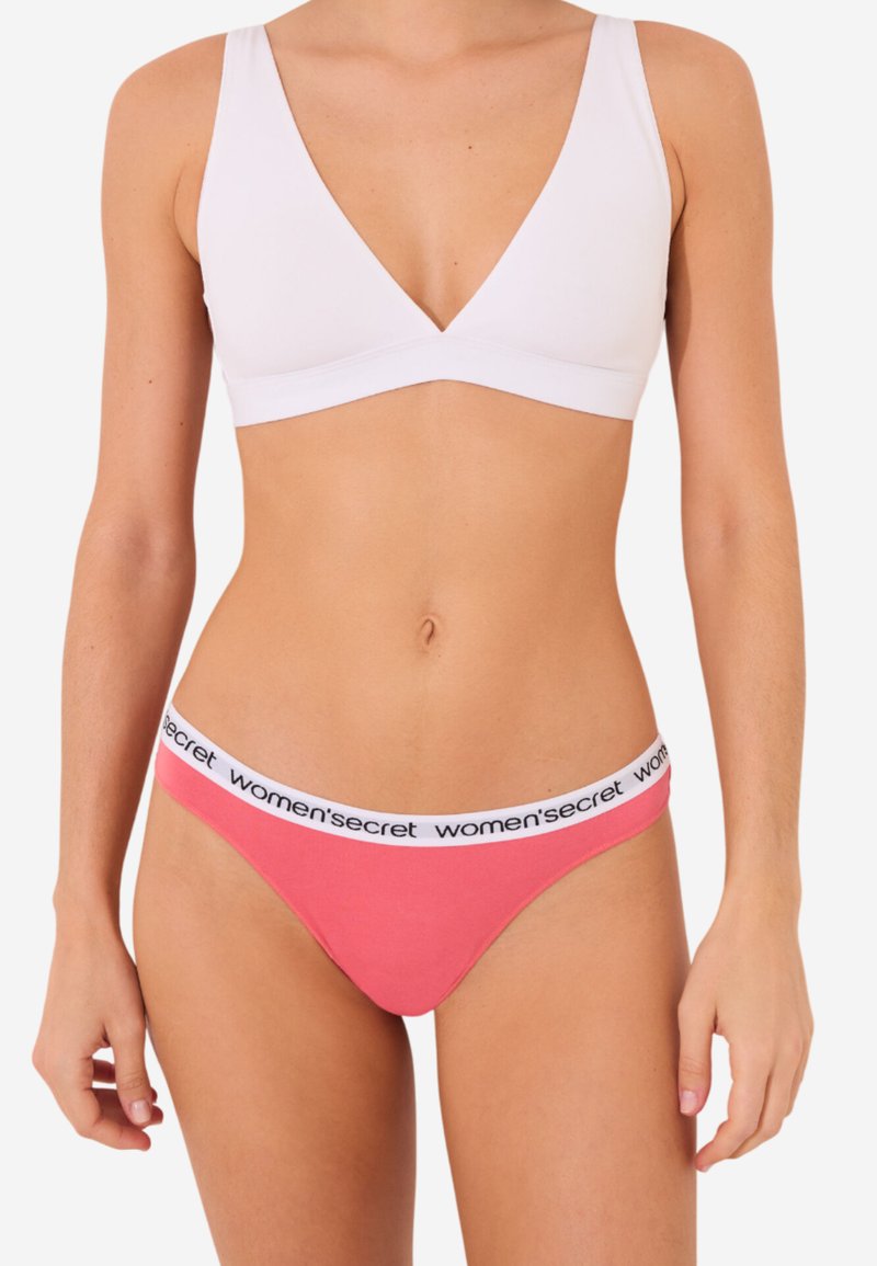 Thong en coton rose avec une taille élastique blanche portant le texte noir "women's secret". Texture lisse et design taille basse.
