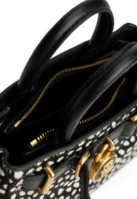 Gestructuurde zwarte leren handtas met witte stippen. Bevat gouden ritsen en hardware. Inclusief dubbele zwarte handvatten voor het dragen.