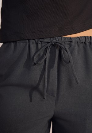 Mørkegrå bukser med vide ben lavet af et blødt, tekstureret stof. Har elastisk talje med snøre og sidelommer.