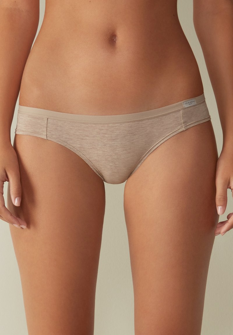 Beige bomullsblandning hipsterunderkläder med en slät textur och sömlösa kanter, utrustade med en smal midjeband och en subtil märkning.