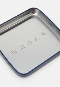 Bandeja de metal cuadrada con un interior plateado cepillado y un borde azul, con texto en relieve que dice "FALKE" en el centro.