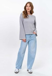 Gray long-sleeve top with a wide neckline, paired with light blue wide-leg jeans and white sneakers with black accents.