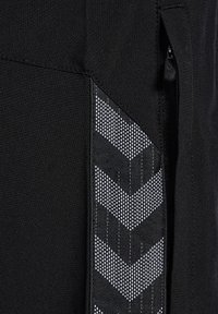 Zwarte stof met een verticale rits en een reflecterende zwart-witte chevronpatroonstrook naast de rits.