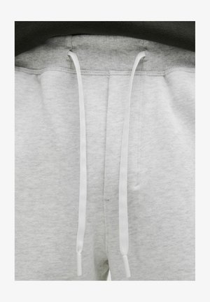 Hallid hallid spordipüksid pehme tekstuuriga, millel on nööriga sulgemine valgete otstega ja soonikkoes vöökoht.